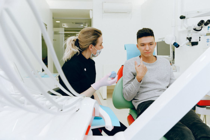 A man in a gray shirt having a dental check-up